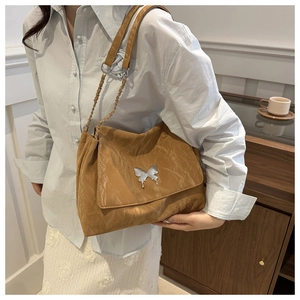 Caramel PU leather pleated shoulder bag with silver butterfly buckle on blue shirt