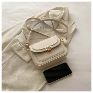Détail du sac bandoulière en cuir crème avec boucle dorée et bandoulière réglable