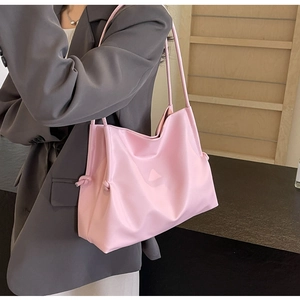Borsa tote rosa minimalista con dettaglio nodo indossata sopra un blazer grigio