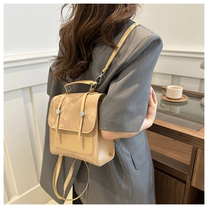 Dettaglio di uno zaino minimalista beige con fibbia e patta indossato da una modella