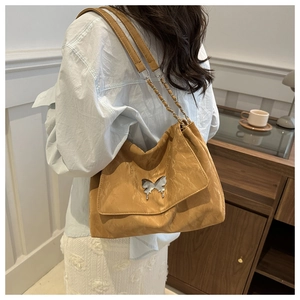 Detail of yellow pleated shoulder bag with silver butterfly buckle and metal chain strap