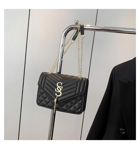Detail der schwarzen Stepptasche mit goldenem S-Verschluss und Metallkettenriemen
