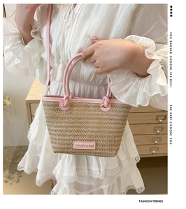 Detailed view of the woven straw bucket bag with pink leather trim and brand label