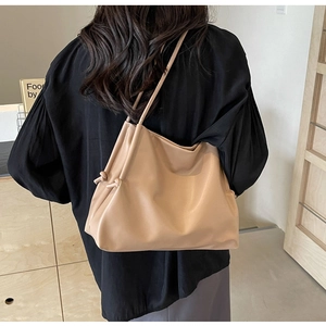 Dettaglio della borsa tote beige minimalista con pelle morbida e coulisse a nodo elegante