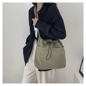 Detail of olive green nylon drawstring crossbody bag with large front pocket and strap