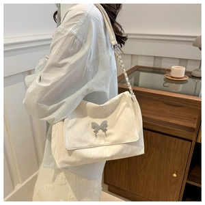 Detail of white PU messenger bag showing silver butterfly clasp and chain strap on shoulder