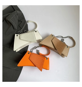 Detail of crocodile pattern faux leather handbags in white, khaki, and orange