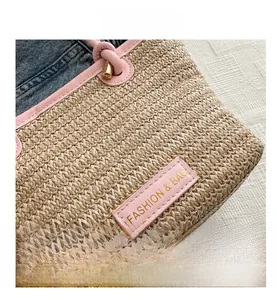 Detail of straw woven bucket bag with pink leather trim and gold fashion logo