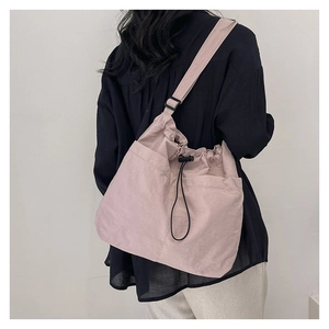 Detail of light purple nylon drawstring bucket bag showing adjustable strap on model
