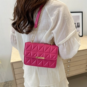 Quilted crossbody bag in magenta with gold chain strap shown on model in modern interior