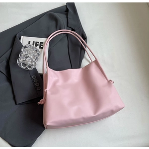 Dettaglio della borsa tote rosa con tracolla annodata e texture in pelle PU minimal