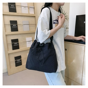 Detailed side view of black drawstring bucket bag with large pocket and nylon strap