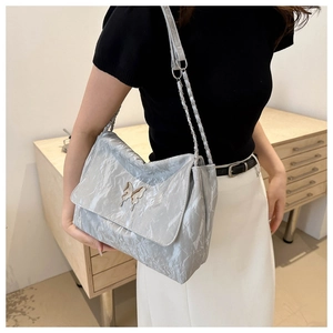 Detail of silver textured PU messenger bag with a metal butterfly clasp and chain strap