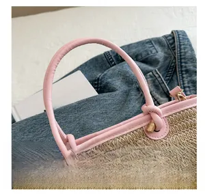 Close-up of woven straw bucket bag with pink faux leather handle and gold hardware
