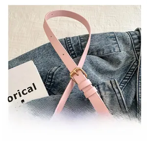 Detail of pink leather belt with gold metal buckle on blue denim jacket texture