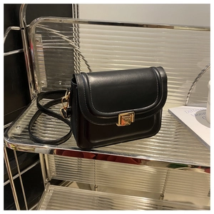 Gros plan du sac en cuir noir montrant la boucle dorée et les coutures fines