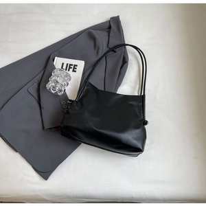 Dettaglio borsa tote in pelle nera opaca con spalline sottili e nodi laterali