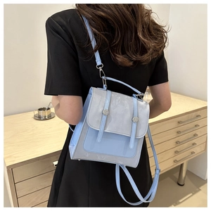 Dettaglio dello zaino mini bicolore con fibbie magnetiche su un elegante abito nero