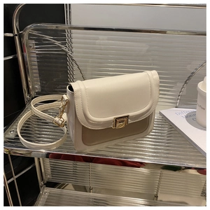 Détail du sac à rabat bicolore avec fermoir rotatif doré et bandoulière fine en cuir PU