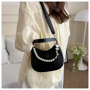 Detail of heart-embossed black crescent bag with pearl and silver heart chain strap