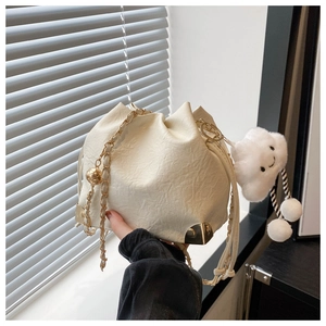 Detail of cream white pleated bucket bag with gold chain and plush cloud charm