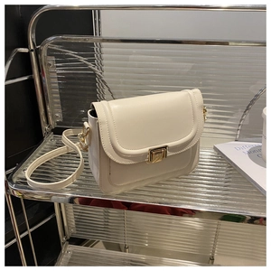 Détail d'un petit sac bandoulière en cuir blanc crème avec un fermoir en métal doré