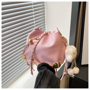 Detail of pink drawstring bucket bag with gold chain and white plush sheep charm