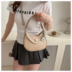 Detail of beige saddle bag featuring pearl and heart metal chains in a stylish interior