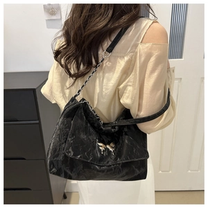 Close-up of black wrinkled PU leather shoulder bag with silver butterfly buckle detail