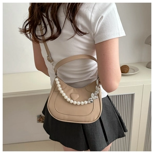 Detail of beige half-moon shoulder bag with pearl heart chain and leather heart patch