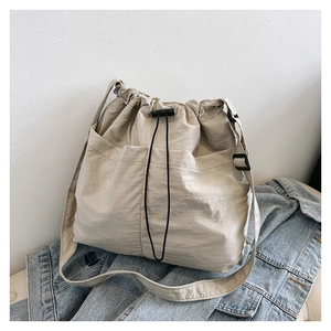 Detail of off-white drawstring crossbody bag featuring nylon fabric and side pocket detail