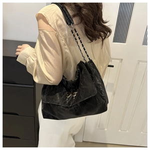 Detail of black PU shoulder bag featuring silver butterfly buckle and chain strap