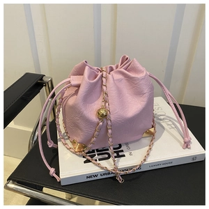 Detail view of pink leather drawstring bucket bag with gold chain and metal sphere buckle