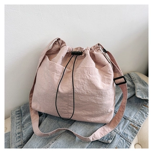 Pink drawstring bucket bag with textured fabric displayed on blue denim jacket