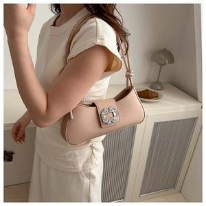 Gros plan du sac baguette beige avec boucle en cristal et bandoulière à nœud