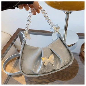 Detail of light blue pleated handbag with metallic butterfly and pearl chain strap