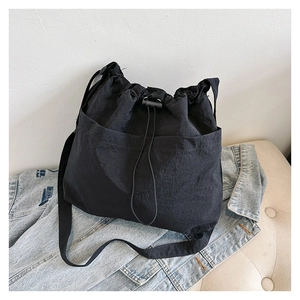 Detail of black drawstring bucket bag with crinkle nylon texture on denim jacket