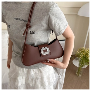 Détail du sac baguette en cuir marron avec une grande boucle carrée en cristal