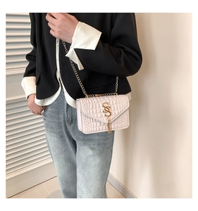 Détail d'un sac bandoulière matelassé crème avec logo S doré et glands métalliques