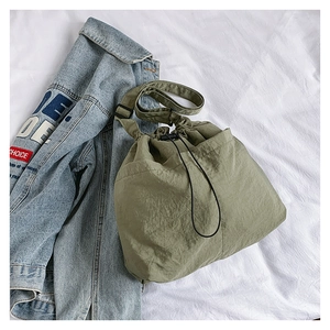 Detail of avocado green nylon drawstring bag with adjustable strap on white fabric