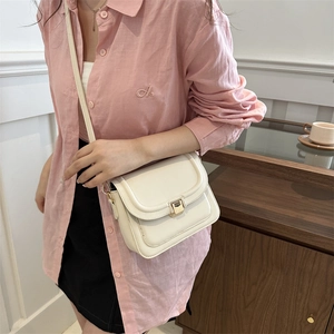 Sac bandoulière carré chic couleur crème avec boucle dorée porté par un mannequin