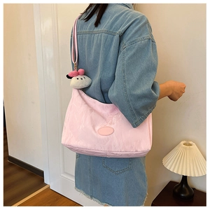 Pink nylon shoulder bag with a cute white puppy plush charm shown on a model