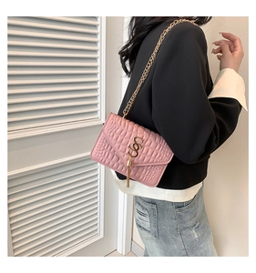 Sac à bandoulière rose matelassé avec chaîne dorée et gland porté par le modèle