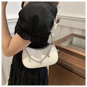 Détail du sac demi-lune crème avec bandoulière à nœud et chaîne argentée à breloques