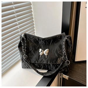 Detailed shot of black pleated PU texture and silver butterfly buckle on chain bag