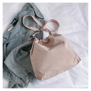 Detailed view of pink drawstring bucket bag paired with a vintage denim jacket
