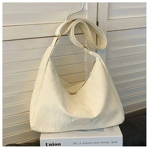 Detail of cream hobo bag showing pleated texture, metal zipper and leather brand logo