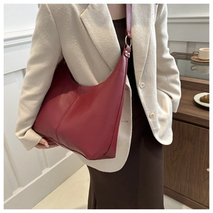 Detail of burgundy leather tote bag with gold ring buckle on model in ivory suit