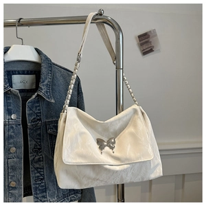 Detail view of cream PU crossbody bag with silver butterfly metal ornament and chain strap