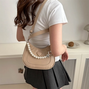 Chic beige hobo bag with heart embossing and pearl chain shown on model